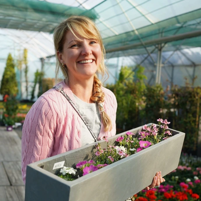 Femme souriante qui tient une jardinière grise en main